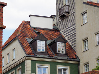 Colorful historic European townhouses with traditional red tile roofs and modern buildings in urban cityscape