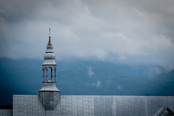 Minimalist shot of a silver church tower on a moody, cloudy day in the Carpathians. The misty...