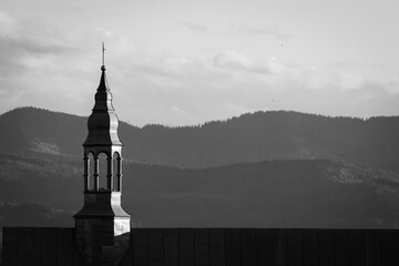 Minimalist black and white photo of a silver church steeple standing against soft Carpathian hills. A timeless composition capturing spiritual stillness and shape