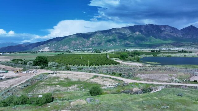 Aerial fruit orchard Utah mountain valley 1 4K. Orchard, farms and rural ranch property. Lake used for irrigation and recreation. Rural landscape in mountain valley. Agricultural. 