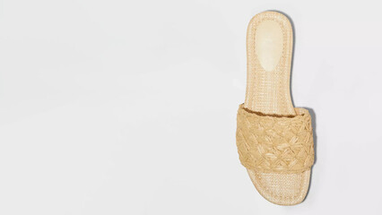 Stylish woven sandal in natural color resting on a light-colored surface, perfect for summer wear