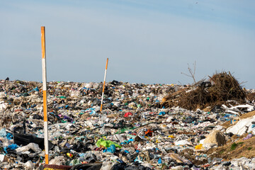 A large landfill site is filled with various types of garbage, highlighting ongoing issues related to waste management and pollution. Trash is scattered across the area