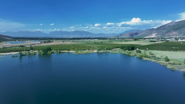 Aerial lake farm fruit orchard Utah mountain valley 1 4K. Orchard, farms and rural ranch property. Lake used for irrigation and recreation. Rural landscape in mountain valley. Agricultural. 
