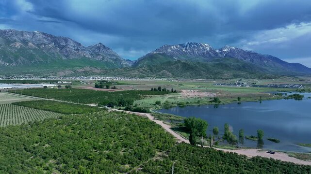 Aerial farm fruit orchard mountain valley lake Utah 2 slide 4K. Orchard, farms and rural ranch property. Lake used for irrigation and recreation. Rural landscape in mountain valley. Agricultural. 