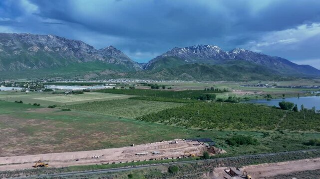 Aerial farm fruit orchard mountain valley lake Utah fast slide. Orchard, farms and rural ranch property. Lake used for irrigation and recreation. Rural landscape in mountain valley. Agricultural. 