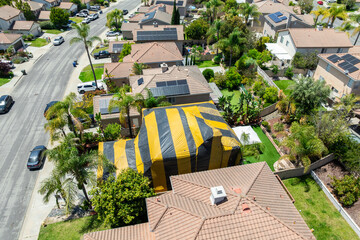 Aerial view of yellow and gray termite tent on a big house in San Diego, South California