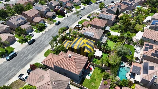 Aerial view of yellow and gray termite tent on a big house in San Diego, South California