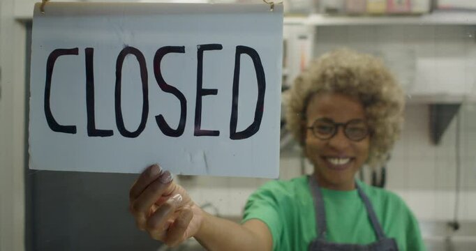Smiling African Woman with Afro Hair Closing Her Small Restaurant for the Day