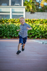 A summer portrait of a cheerful blond boy in a checkered shirt.