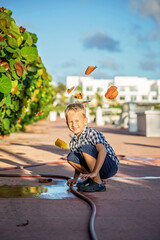 A summer portrait of a cheerful blond boy in a checkered shirt.