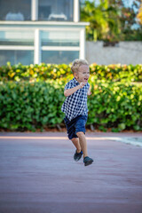A summer portrait of a cheerful blond boy in a checkered shirt.