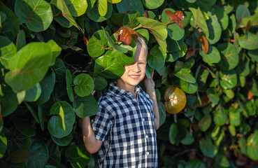 A summer portrait of a cheerful blond boy in a checkered shirt.