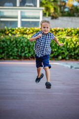 A summer portrait of a cheerful blond boy in a checkered shirt.