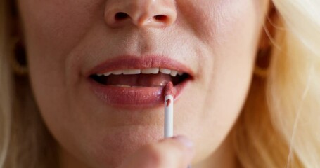 Close-up of a woman's lips during makeup application. A woman paints her lips with lip gloss - Powered by Adobe