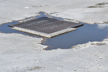 Storm drain in parking lot. Puddles left over from storm.