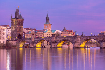 Charles Bridge and historic towers at sunset over Vltava River in Prague, Czech Republic
