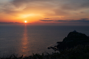 朝焼けの朝 対岸の山並みから昇る朝日 光る海