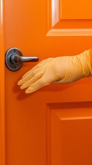A gloved hand reaches for a sleek, modern door handle against a vibrant orange door, symbolizing entry, access, and change in a bold and energetic setting.