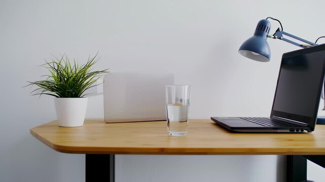 Minimalist workspace setup with laptop, plant, and water glass, perfect for remote work and study