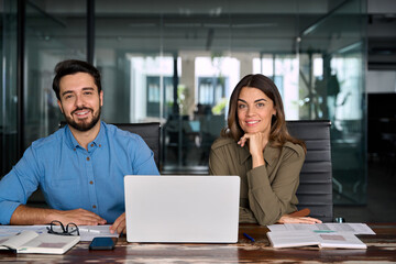 Business team of two professionals mature business woman and young business man corporate managers colleagues sitting in office with laptop, 2 diverse colleagues executives team together, portrait.