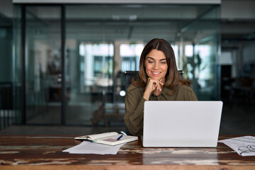 Smiling professional middle aged female company executive manager working looking at computer at workplace. Happy busy mature business woman entrepreneur in office using laptop at work.