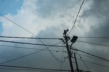 A striking perspective of a utility pole with tangled electrical wires stretching across a dramatic...