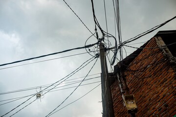 A striking perspective of a utility pole with tangled electrical wires stretching across a dramatic...
