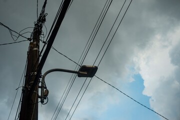 A striking perspective of a utility pole with tangled electrical wires stretching across a dramatic...