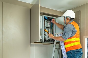 Professional Electrician Installing and Inspecting Electrical Panel in Indoor Wall Electrical Cabinet with Tools and Safety Gear