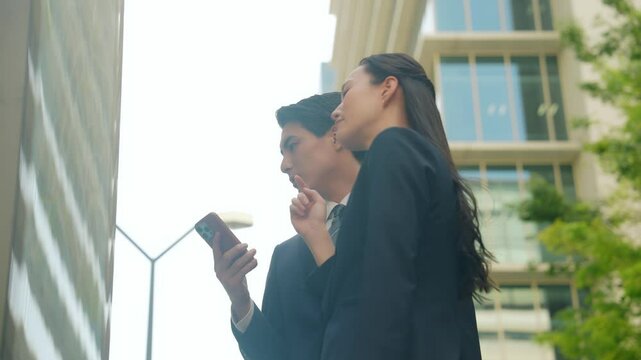 ガイドマップとスマホを見て場所を確認する男女ビジネスパーソン