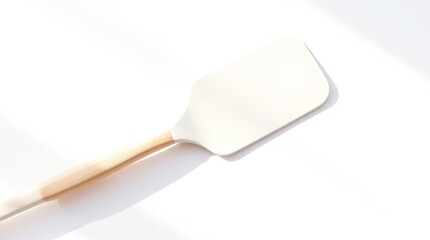 Cream-colored spatula on white background,  light shadows