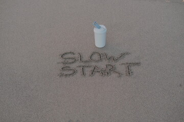 Slow Start – Handwritten Message on Volcanic Sand with Thermos Mug