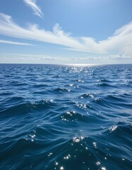 Fototapeta premium photorealistic seascape with calm blue waters reflecting a bright sky and wispy clouds.