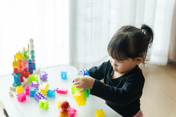 3-year-old girl happily playing with toy blocks at home.Childhood and children's meditation concept