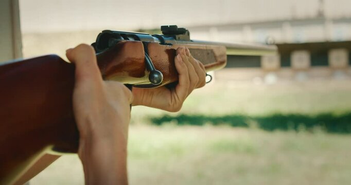Woman holding a wooden rifle in aiming position and firing on range target outdoors