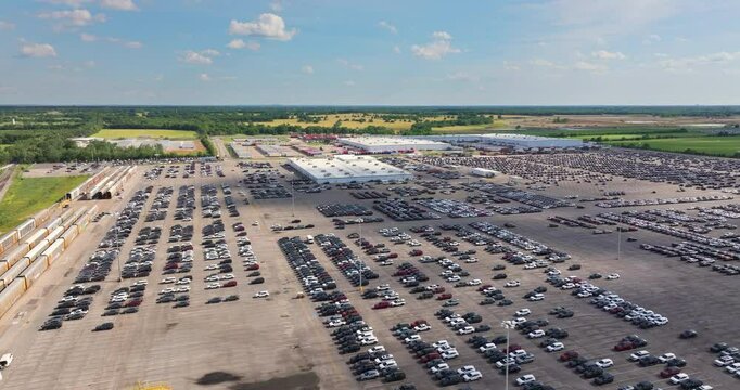 Parked new cars at the automotive plant factory parking lot ready for sale. Development of American industry concept.