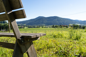 Wooden bench in green meadow with mountain landscape 