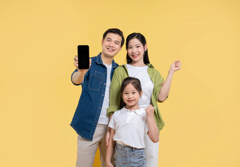 Cheerful family smiles together dad holds up smartphone on a bright yellow background