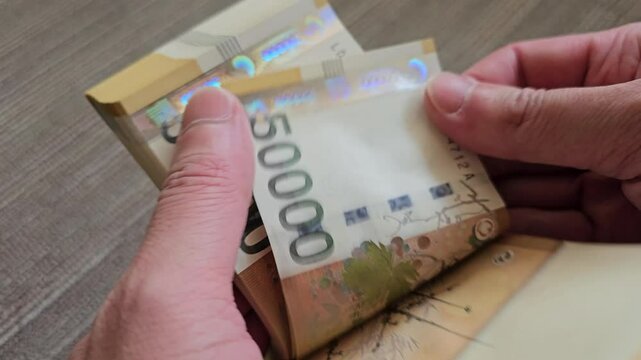 A person counting 50,000 won notes, the highest denomination among paper currency in circulation in Korea, by hand