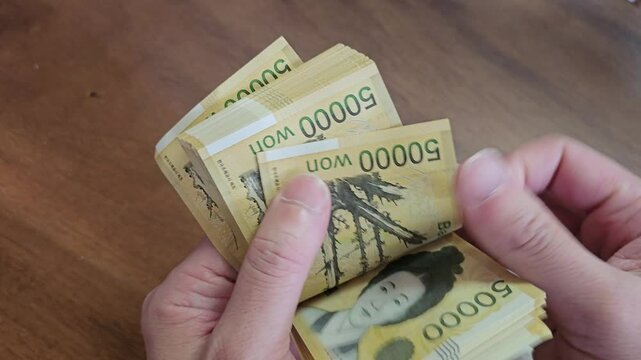 A person counting 50,000 won notes, the highest denomination among paper currency in circulation in Korea, by hand