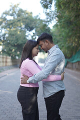Obraz premium A joyful young couple sharing a loving moment on a peaceful street surrounded by greenery