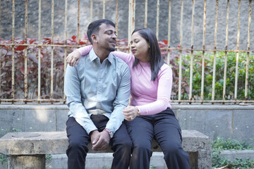 A joyful young couple sharing a loving moment on a peaceful street surrounded by greenery