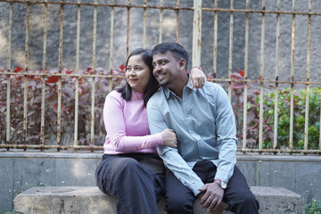 A joyful young couple sharing a loving moment on a peaceful street surrounded by greenery