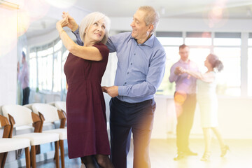 Elderly man and elderly woman dance ballroom dance waltz in studio