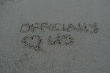 Officially Us Message on Volcanic Sand with Heart Symbol