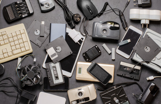 Old electronic devices on a black background. The concept of recycling used gadgets.