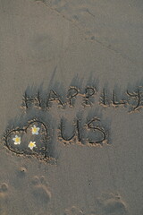 Happily Us Message on Volcanic Sand with Heart and Frangipani Flowers