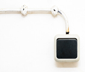 Vintage light switch with exposed wire on white wall old electrical detail