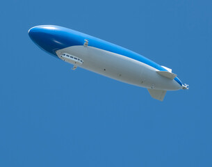 Zeppelin in a clear blue sky. Rigid, cigar-shaped airship made of a lightweight skeleton with bags filled with a light gas