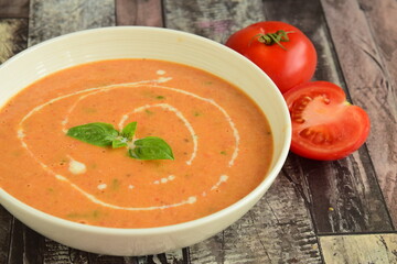 Tomato soup in a bowl garnish with basil and cream